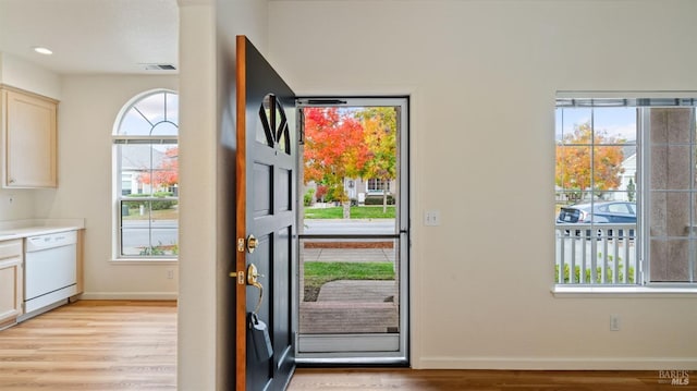 doorway featuring light wood finished floors, plenty of natural light, visible vents, and baseboards