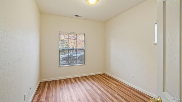 empty room featuring light wood-type flooring, baseboards, and visible vents