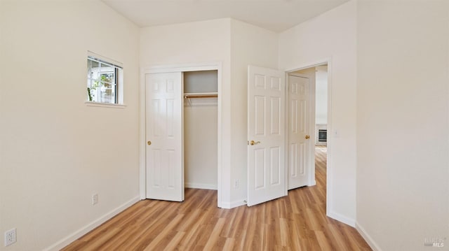 unfurnished bedroom featuring light wood-style floors, baseboards, and a closet