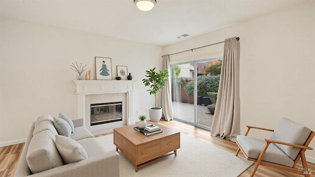 living area featuring light wood-type flooring, visible vents, baseboards, and a high end fireplace