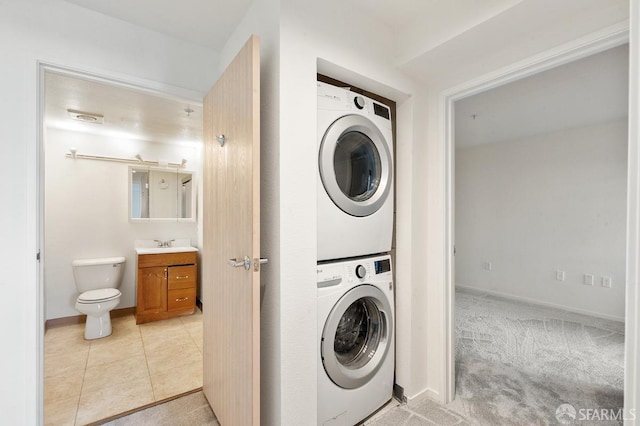 laundry room featuring stacked washer / drying machine, light colored carpet, and sink