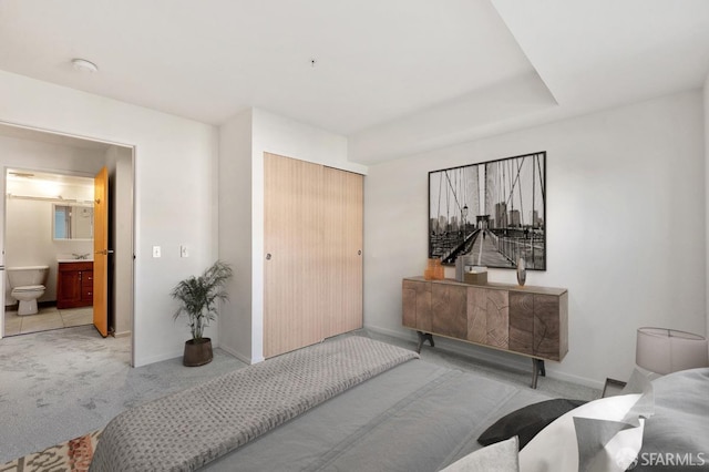 bedroom featuring connected bathroom, a closet, and light colored carpet