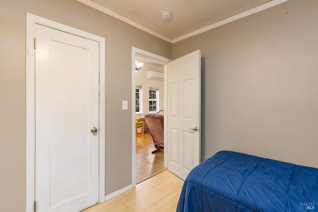 bedroom featuring hardwood / wood-style floors, crown molding, and a wall mounted AC