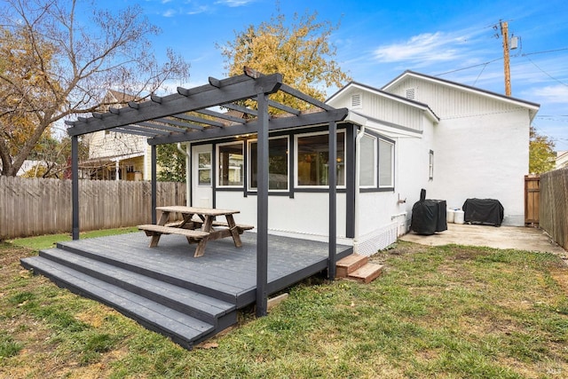 rear view of property featuring a pergola, a deck, a sunroom, and a lawn