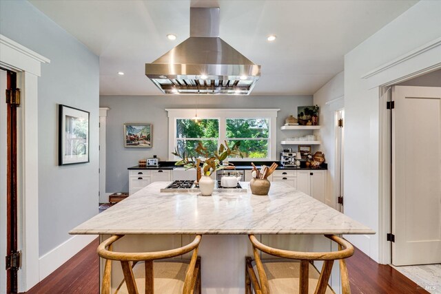 kitchen with a center island, island exhaust hood, a kitchen bar, and stainless steel gas cooktop