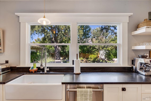 kitchen featuring sink, decorative light fixtures, white cabinetry, and a wealth of natural light