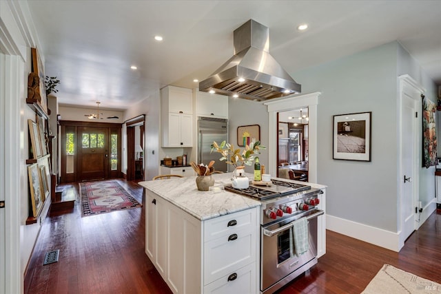 kitchen featuring premium appliances, white cabinets, island exhaust hood, light stone countertops, and a center island