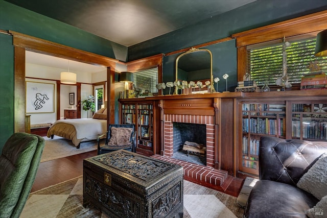 living area with hardwood / wood-style flooring, a wealth of natural light, and a brick fireplace