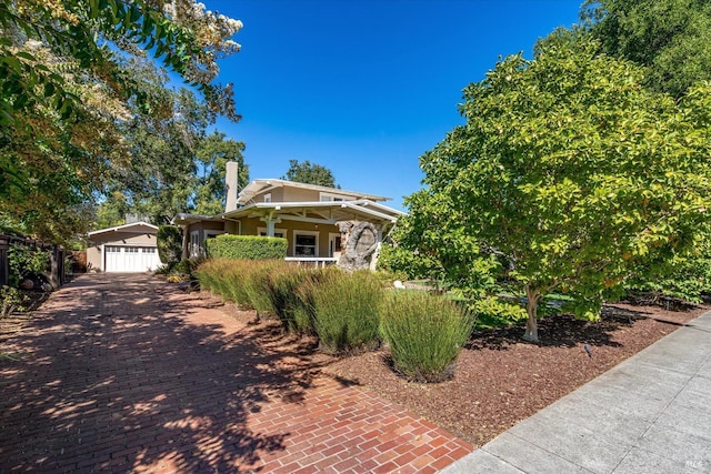 view of property hidden behind natural elements featuring a garage and an outdoor structure