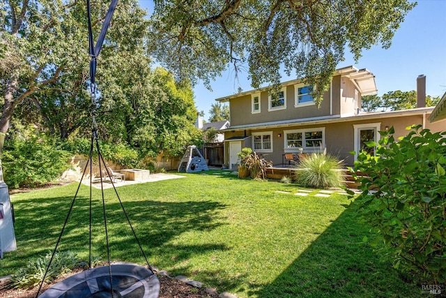 rear view of house featuring a fire pit, a patio area, and a yard