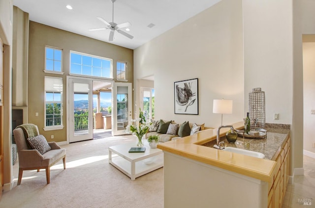 living room featuring a ceiling fan, baseboards, recessed lighting, a towering ceiling, and light carpet