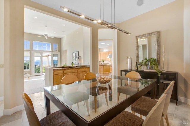 dining area featuring light tile patterned floors, recessed lighting, a high ceiling, and baseboards