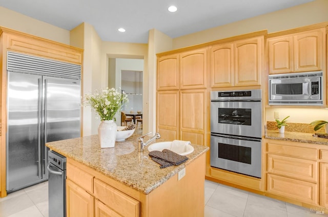 kitchen with built in appliances, light tile patterned flooring, light brown cabinets, and light stone countertops