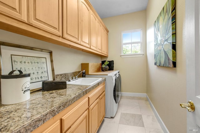 laundry area with baseboards, light tile patterned floors, washer and dryer, cabinet space, and a sink