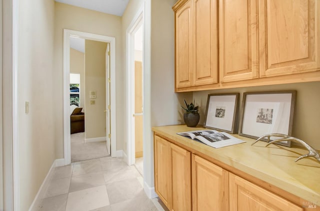 kitchen with baseboards, light brown cabinetry, and light countertops