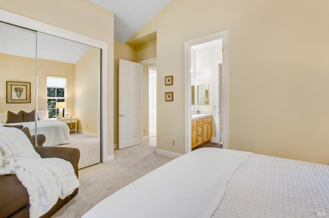 bedroom featuring light carpet, lofted ceiling, a closet, connected bathroom, and baseboards