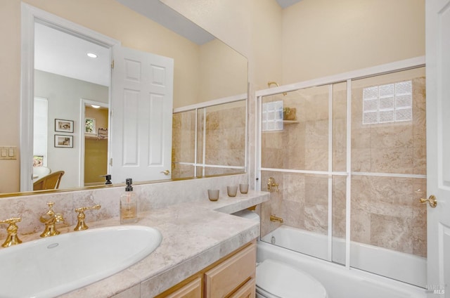 bathroom with toilet, vanity, and bath / shower combo with glass door