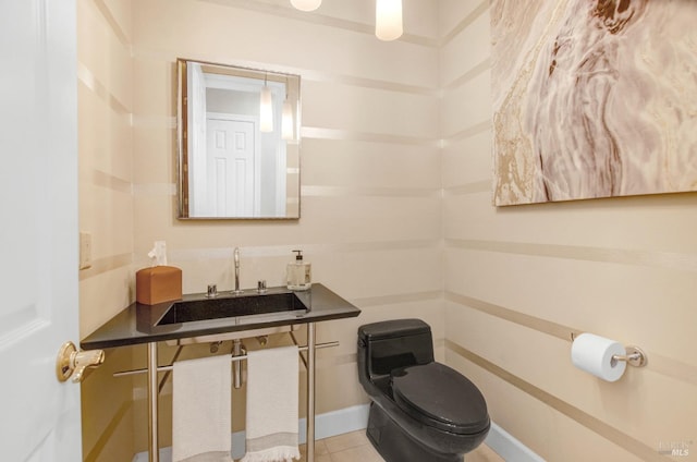 half bathroom featuring tile patterned flooring, toilet, and a sink