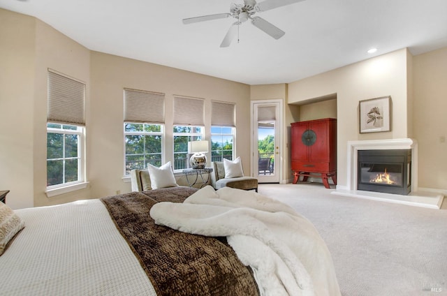 carpeted bedroom with a glass covered fireplace, recessed lighting, ceiling fan, and access to outside