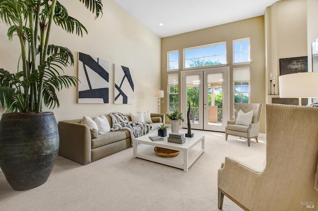 carpeted living area featuring recessed lighting, french doors, and a towering ceiling