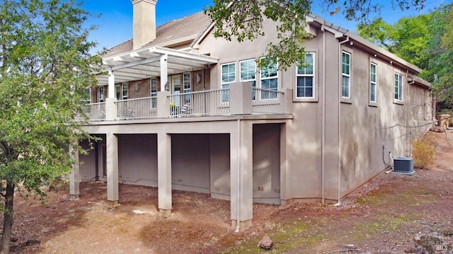 back of house featuring stucco siding, central AC unit, a pergola, and a chimney