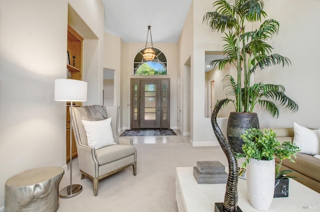 entrance foyer with baseboards, light carpet, and a towering ceiling