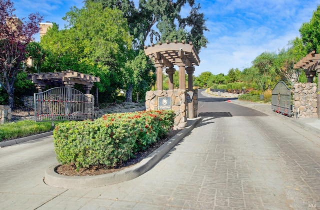 view of street featuring a gate, curbs, and a gated entry