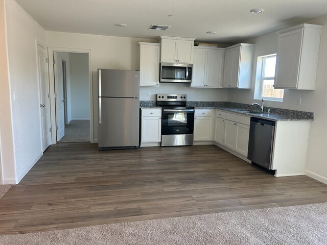 kitchen featuring dark hardwood / wood-style flooring, white cabinetry, sink, and stainless steel appliances