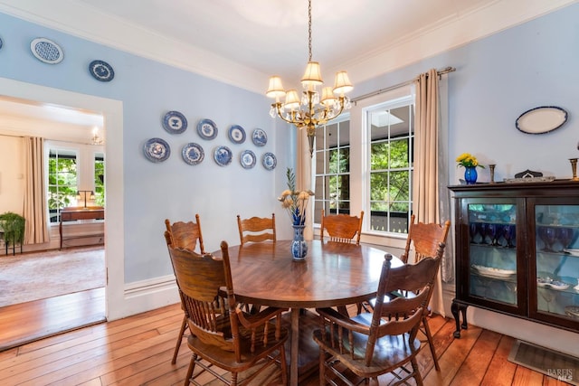 dining area with ornamental molding, wood-type flooring, and an inviting chandelier