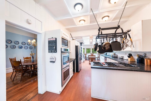 kitchen with appliances with stainless steel finishes, backsplash, coffered ceiling, white cabinets, and hardwood / wood-style floors