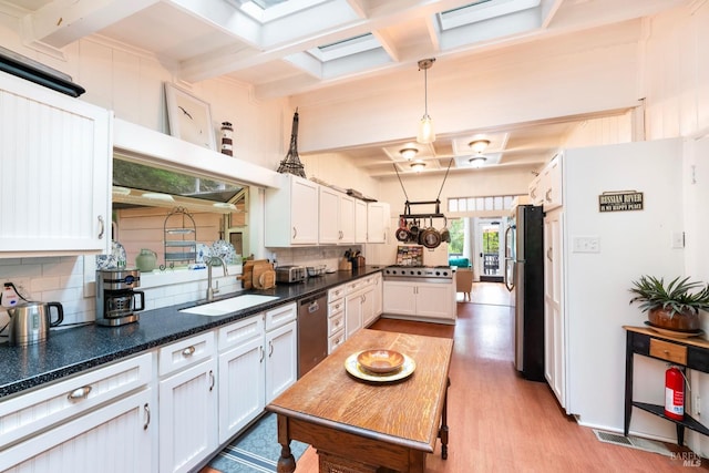 kitchen with sink, backsplash, decorative light fixtures, white cabinets, and appliances with stainless steel finishes