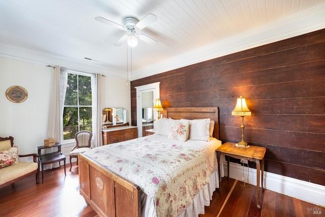 bedroom featuring hardwood / wood-style floors, crown molding, wooden walls, ceiling fan, and wood ceiling