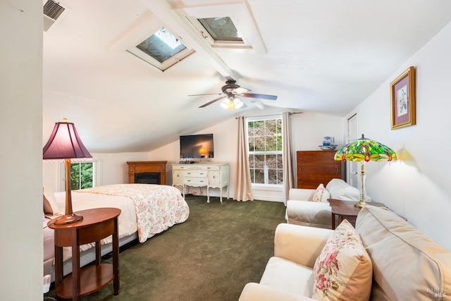 bedroom with ceiling fan, vaulted ceiling with skylight, and dark carpet