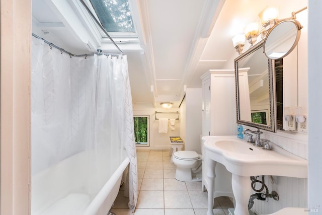 bathroom featuring a skylight, ornamental molding, shower / tub combo with curtain, tile patterned flooring, and toilet