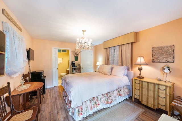 bedroom featuring dark hardwood / wood-style flooring, connected bathroom, and a chandelier