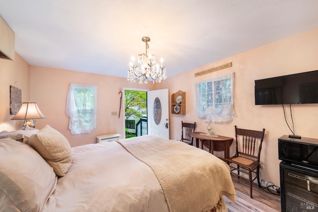 bedroom featuring a notable chandelier, access to outside, and light hardwood / wood-style flooring