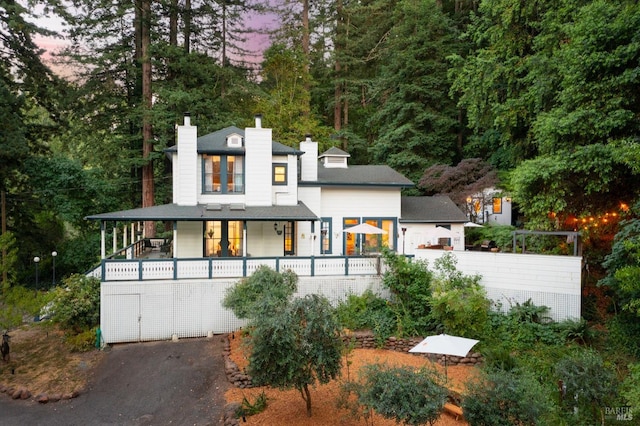 back house at dusk featuring a porch