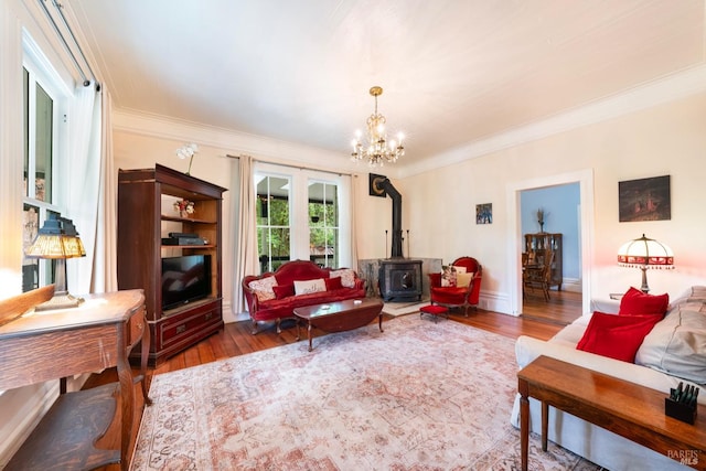 living room with a wood stove, dark wood-type flooring, a notable chandelier, and ornamental molding