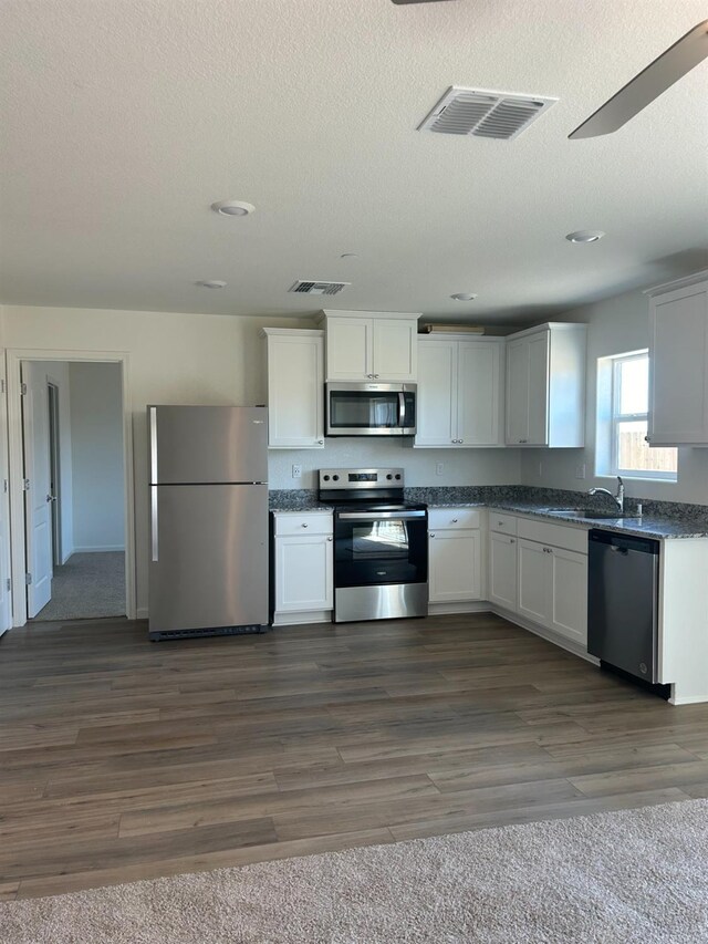 kitchen with dark countertops, visible vents, appliances with stainless steel finishes, and dark wood-type flooring