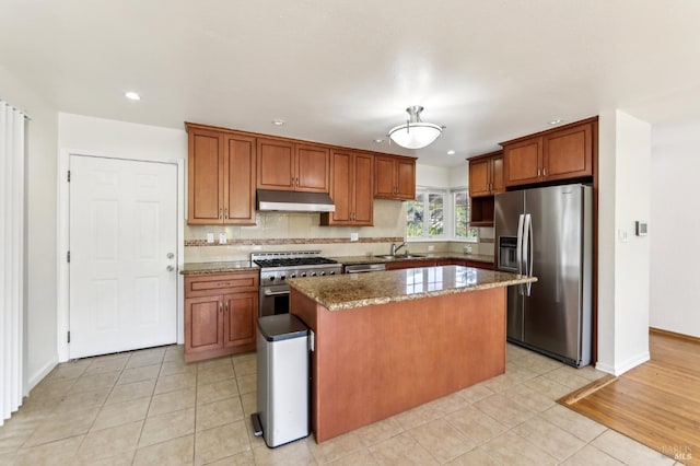 kitchen featuring sink, light stone countertops, light tile patterned floors, a kitchen island, and stainless steel appliances