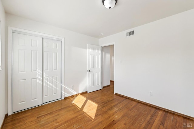 unfurnished bedroom with wood-type flooring and a closet