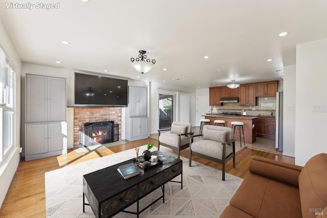 living room featuring light hardwood / wood-style flooring and a brick fireplace