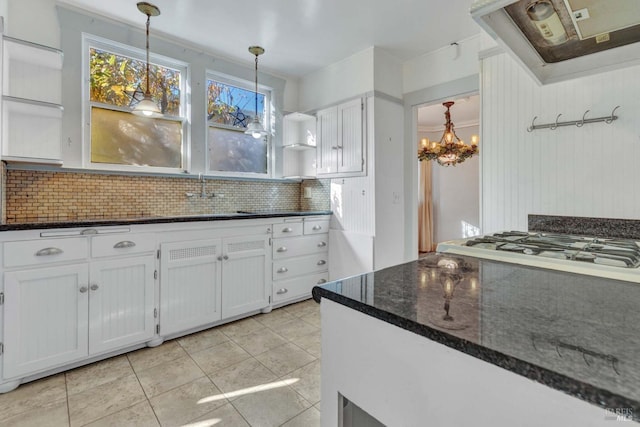 kitchen with pendant lighting, dark stone countertops, range hood, white cabinets, and decorative backsplash