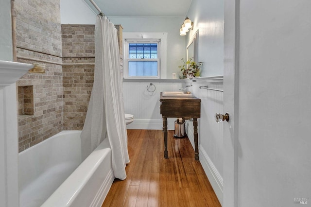 bathroom with hardwood / wood-style flooring, shower / bath combination with curtain, and toilet