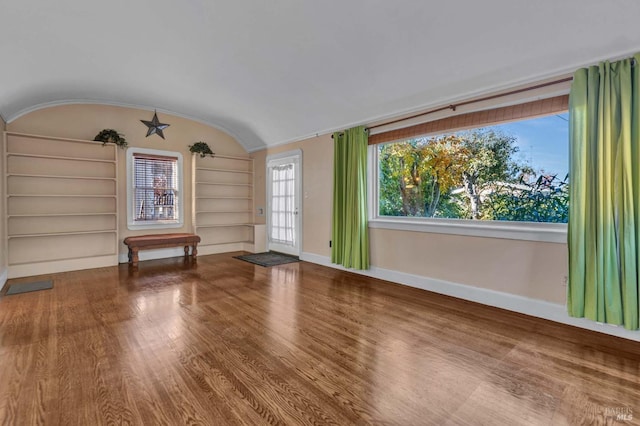 unfurnished room with lofted ceiling, hardwood / wood-style flooring, and built in shelves