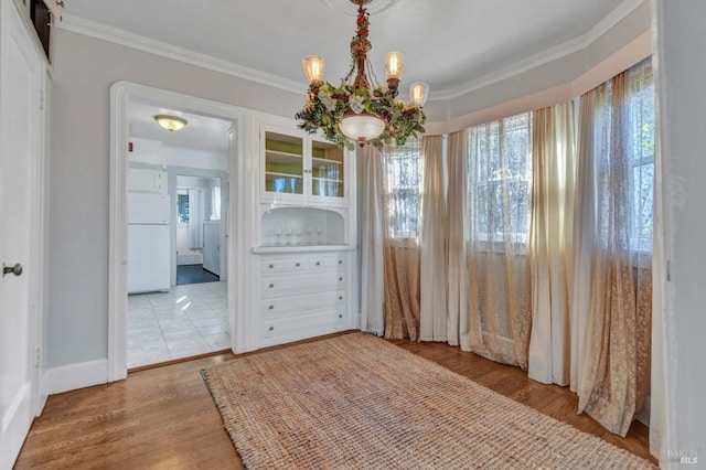 dining space featuring an inviting chandelier, crown molding, and light hardwood / wood-style floors