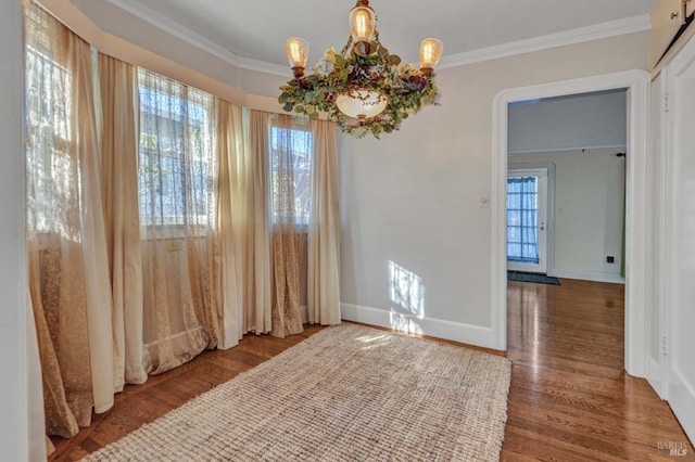 unfurnished dining area with ornamental molding, dark hardwood / wood-style floors, and an inviting chandelier