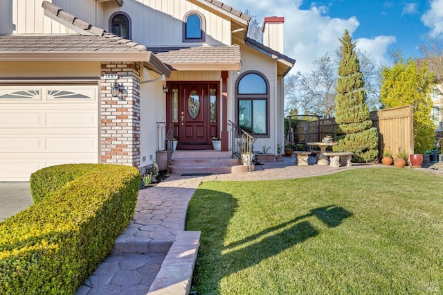 view of exterior entry featuring a yard and a garage