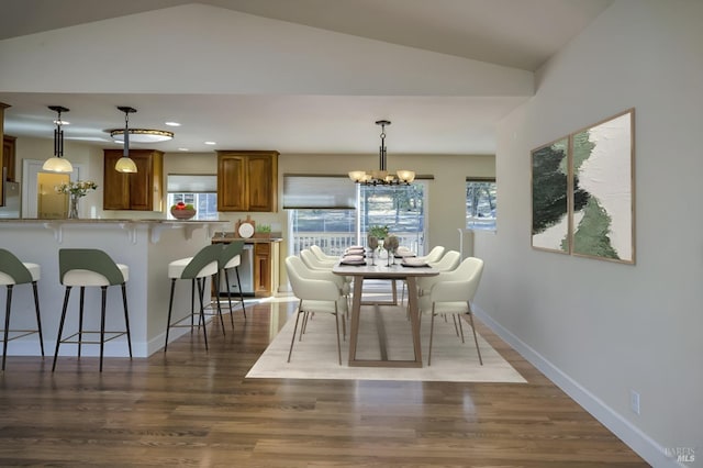 dining room with hardwood / wood-style floors, lofted ceiling, and an inviting chandelier