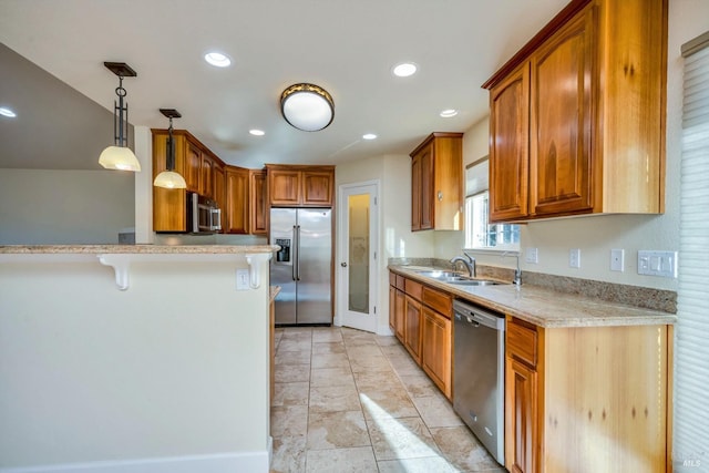 kitchen featuring hanging light fixtures, sink, light stone countertops, appliances with stainless steel finishes, and a breakfast bar area